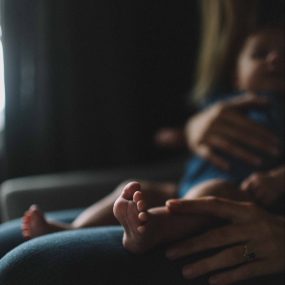 baby sits on parents lap with feet in focus
